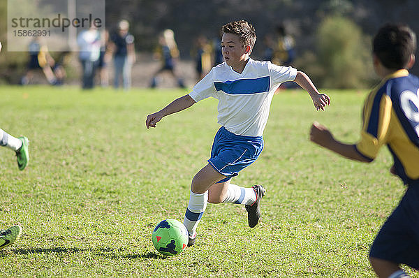 Jugendlicher Fußballspieler dribbelt Ball durch die Verteidiger
