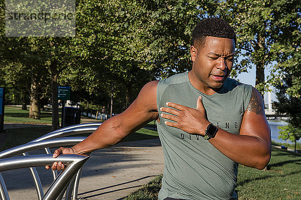 athletischer Mann in Laufkleidung streckt sich in einem Stadtpark