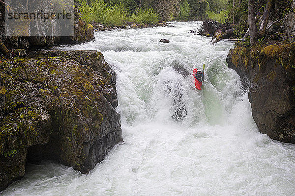Ein Wildwasser-Kajakfahrer paddelt über einen Wasserfall auf dem Fluss Cheakamus.