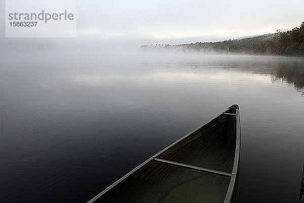 Ein schnittiges Kanu  das an einem Dock an einem ruhigen Teich in Maine festgemacht ist.
