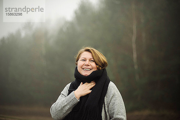 Frau steht bei nebligem Wetter am Wald