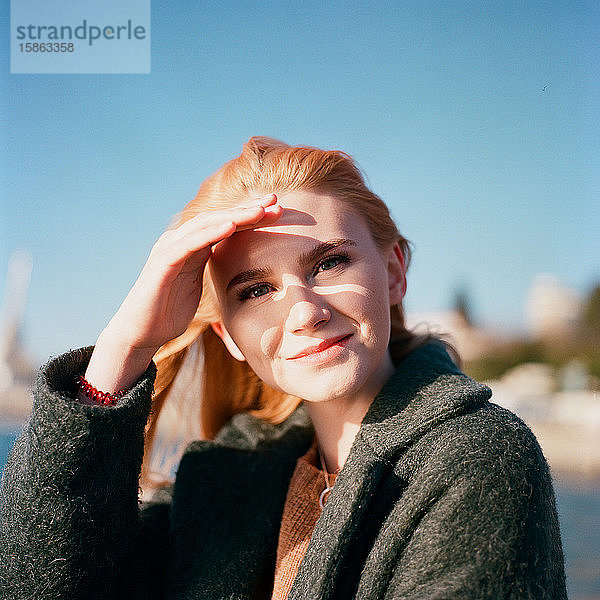 Eine schöne Frau sitzt allein auf dem Pier und lächelt