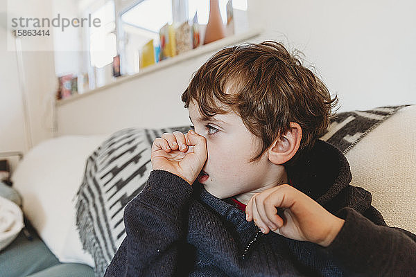 Seitenansicht eines Jungen mit Schnupfen oder Grippe haltender Nase