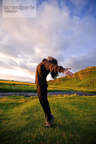 Chinesische Frau streckt sich bei Sonnenuntergang in Island
