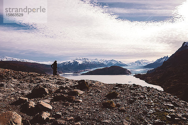Mann steht auf Felsen am See mit Gletschern
