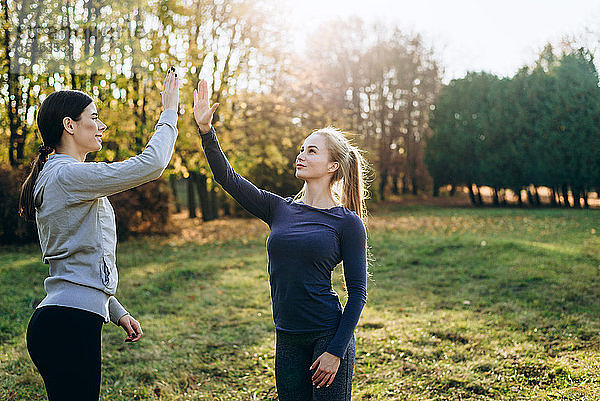 Zwei Mädchen im Park treiben Sport und klatschen in die Hände.