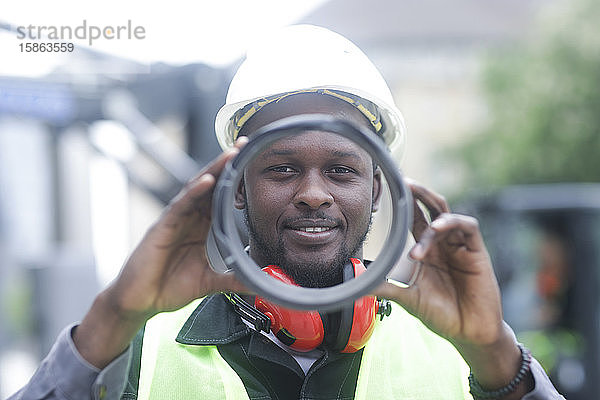 Arbeiter junger Mann mit Helm  der nach draußen auf ein Rohr schaut