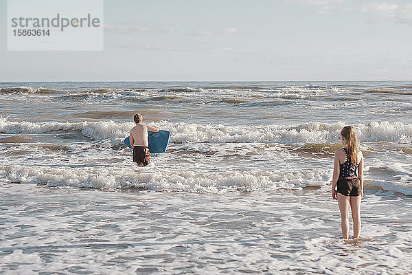 Junge und Mädchen spielen in den Wellen am Strand