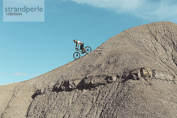 Seitenansicht eines Mountainbikers auf steilem Wüstengelände