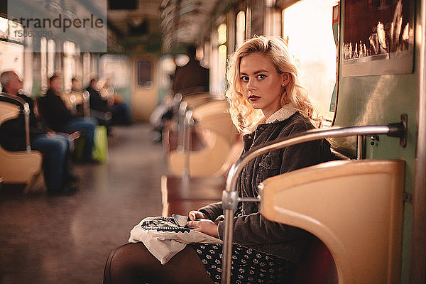 Junge Frau schaut in die Kamera  während sie in der U-Bahn fährt