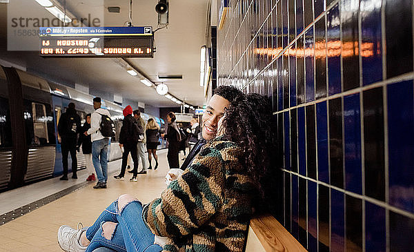 Paar  das in der U-Bahn-Station sitzt und gemeinsam auf einen Zug wartet