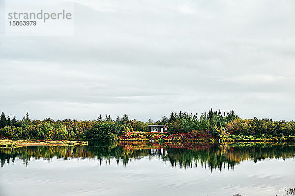 Ruhige Landschaft eines einsamen Hauses inmitten eines Waldes am Ufer des Sees