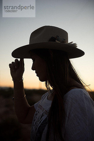 Eine Frau mit ihrem geliebten Cowboyhut erkundet den Sonnenuntergang in Joshua Tree