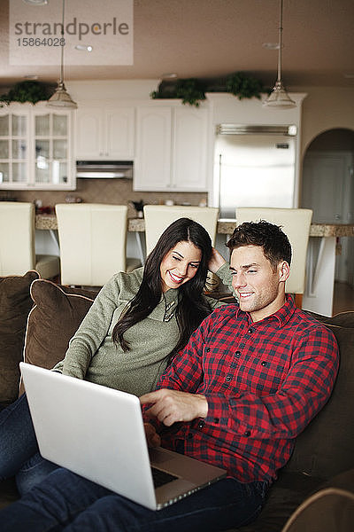 Ehepaar mit Laptop im Wohnzimmer