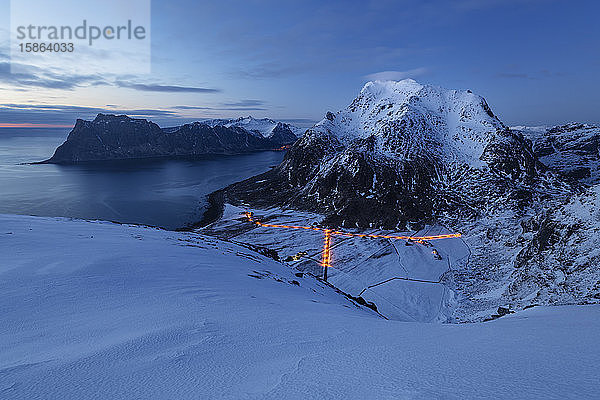 Die Lichter des Dorfes Uttakleiv leuchten in der WinterdÃ?mmerung unter den Berggipfeln von Himmeltindan  VestvÃ¥gÃ¸y  Lofoten-Inseln  Norwegen