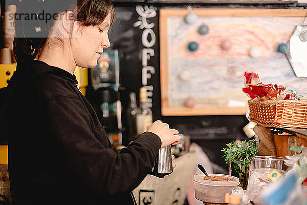 Weiblicher Barista  der im Café stehend Kaffee zubereitet