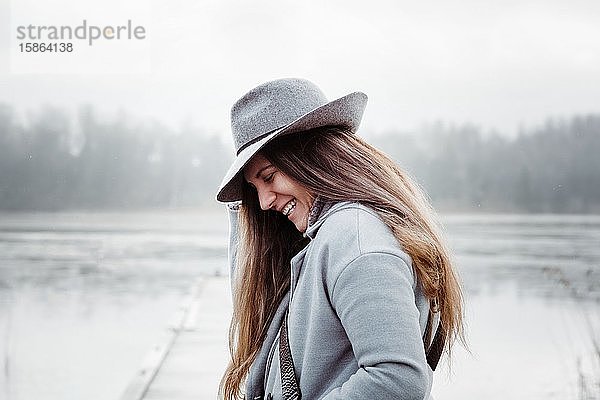 Profil einer Frau mit langen braunen Haaren und einem Hut auf lächelndem Lächeln