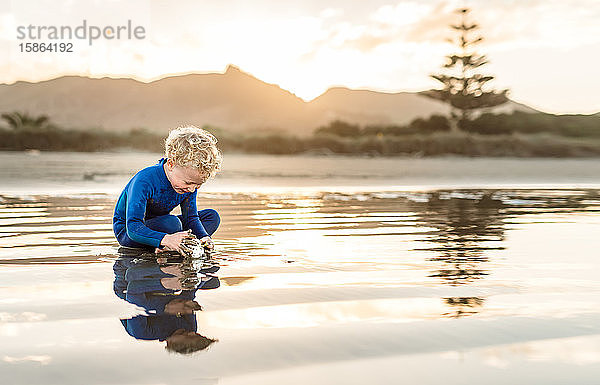 Fröhliche Vorschulkinder spielen in der Abenddämmerung am Strand