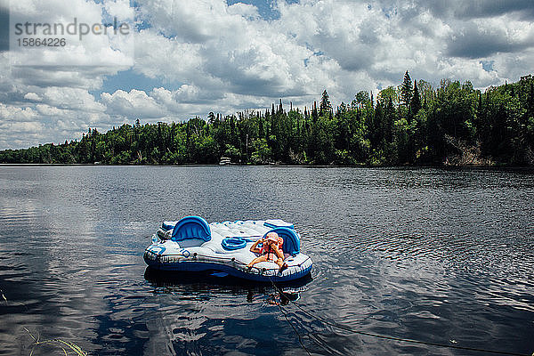 Kleinkind liegt auf einem schwimmenden Floß auf einem Fluss im nördlichen Ontario