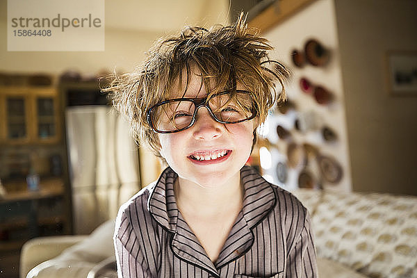 Porträt eines sechsjährigen Jungen mit zerzaustem Haar und übergroßer Brille beim Aufwachen. Betthaar.