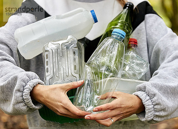 Frau hält einen Arm voll gebrauchter Plastikverpackungen und Flaschen