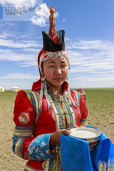 Frau mit roter Mütze und spitzem Hut und silberner Schale mit Milch zur Begrüßung von Besuchern  Wüste Gobi  bei Bulgan  Omnogov  Mongolei  Zentralasien  Asien