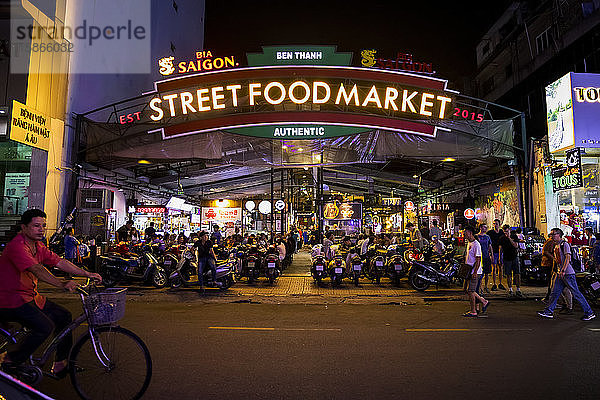 Nächtlich beleuchteter Street Food Market mit Motorrädern und Menschen draußen an der Straße; Ho-Chi-Minh-Stadt  Vietnam