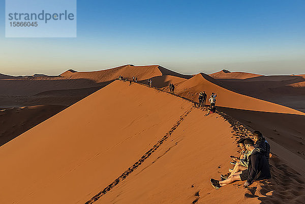 Touristen genießen den Sonnenaufgang von der Düne 45  Sossusvlei  Namib-Wüste; Namibia