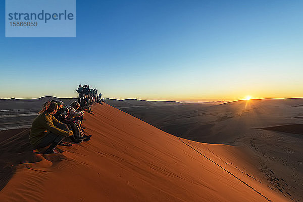 Touristen genießen den Sonnenaufgang von der Düne 45  Sossusvlei  Namib-Wüste; Namibia