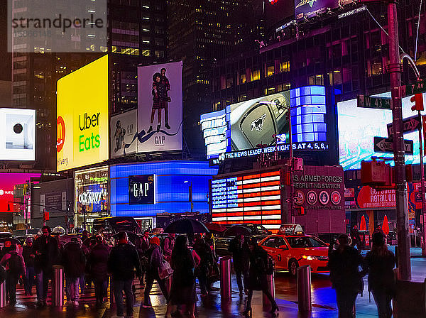 Times Square Werbung beleuchtet in der Nacht mit Touristen entlang der Straße  Midtown Manhattan; New York City  New York  Vereinigte Staaten von Amerika