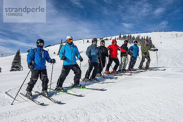 In einer Reihe stehende Skifahrer  die auf einer verschneiten Piste für die Kamera posieren; British Columbia  Kanada