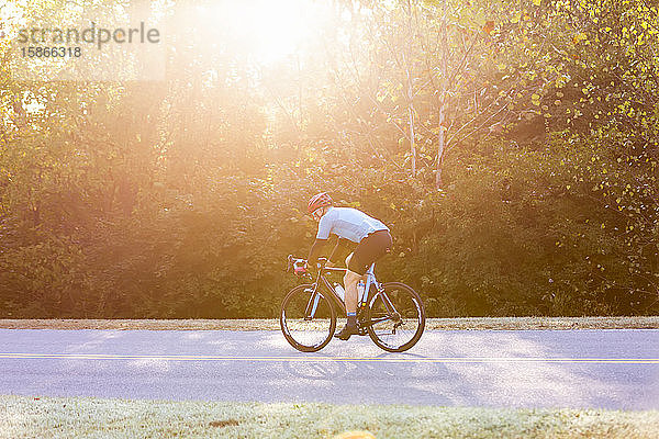 Radfahrer auf einer Straße mit hellem Sonnenlicht  das durch die Bäume fällt  in der Nähe der Trace Nachez Bridge; Franklin  Tennessee  Vereinigte Staaten von Amerika
