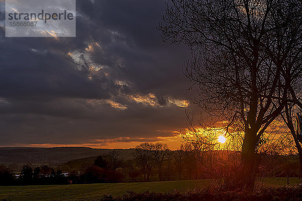Goldener Sonnenuntergang leuchtend am Himmel mit dunklen Wolken über der Landschaft; Ravensworth  North Yorkshire  England