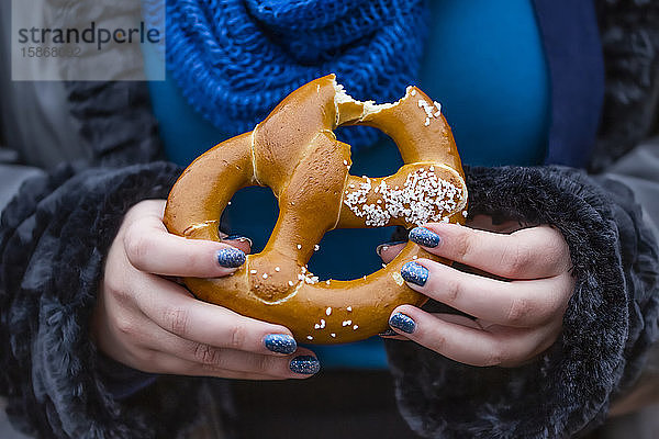 Frau isst eine Brezel; New York City  New York  Vereinigte Staaten von Amerika