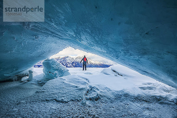 Zerkleinertes Eis nimmt entlang der Küste des Kluane National Park wunderschöne Muster und Formen an. Ein Mann mit Trekkingstöcken blickt auf den zugefrorenen See; Haines Junction  Yukon  Kanada