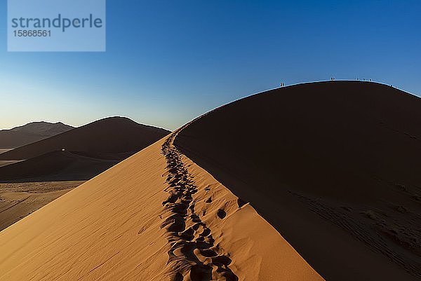 Silhouette von Touristen beim Besteigen der Düne 45 in der Morgendämmerung  Sossusvlei  Namib-Wüste; Namibia