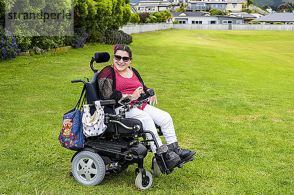 Maori-Frau mit Cerebralparese in einem Rollstuhl auf einer Rasenfläche in einem Park; Wellington  Neuseeland