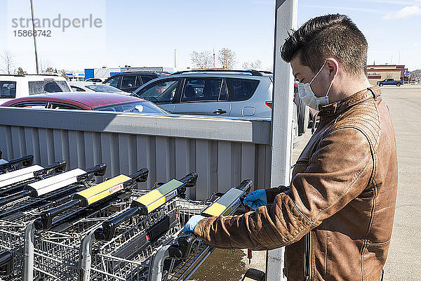 Ein junger Mann bekommt einen Einkaufswagen während der Covid-19-Weltpandemie; Edmonton  Alberta  Kanada