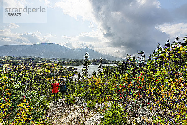 Zwei Frauen stehen auf einem Felsen und überblicken die Landschaft am Wright Pass nahe der Grenze zwischen Kanada und den USA; Yukon  Kanada