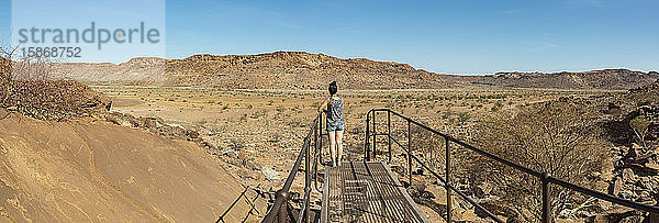 Frau auf einem Steg in Twyfelfontein  einer alten Felsgravurstätte  Damaraland; Kunene-Region  Namibia
