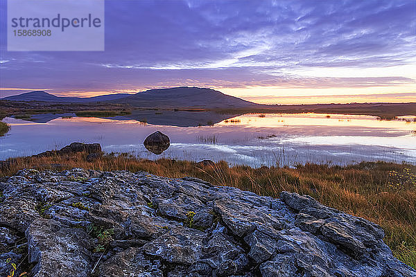 Kleiner See im Burren-Nationalpark mit einem kleinen Hügel im Hintergrund in der Morgendämmerung  Burren-Nationalpark; Grafschaft Clare  Irland