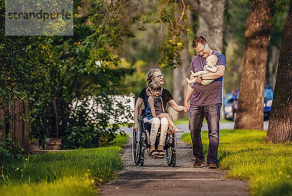 Eine Familie  die abends spazieren geht; die Mutter ist querschnittsgelähmt und sitzt im Rollstuhl; Edmonton  Alberta  Kanada