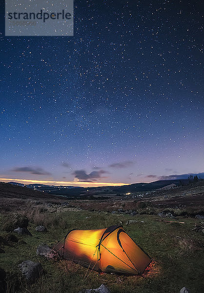 Ein beleuchtetes Zelt in den Wicklow Mountains bei Nacht mit Sternen am Himmel; County Wicklow  Irland