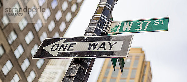 Straßenschilder an einem Pfosten  eine Einbahnstraße und West 37th Street  Manhattan; New York City  New York  Vereinigte Staaten von Amerika