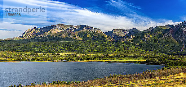 Panorama einer Bergkette entlang eines Seeufers mit blauem Himmel und Wolken  Waterton Lakes National Park; Waterton  Alberta  Kanada