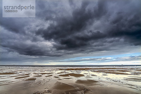 Dunkle Sturmwolken über dem Atlantischen Ozean mit nassem Sandstrand im Vordergrund; South Shields  Tyne and Wear  England