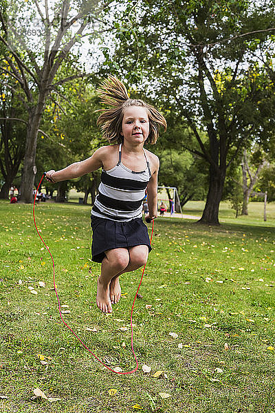 Ein junges Mädchen hüpft mit einem Springseil in einem Park; Edmonton  Alberta  Kanada