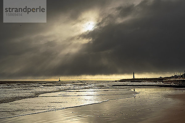 Silhouettierte Leuchttürme entlang der Küstenlinie unter dramatischem Wolkenhimmel; Whitburn Village  Tyne and Wear  England