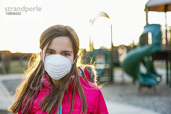 Junges Mädchen steht auf einem Spielplatz und trägt eine Schutzmaske zum Schutz vor COVID-19 während der weltweiten Coronavirus-Pandemie; Toronto  Ontario  Kanada