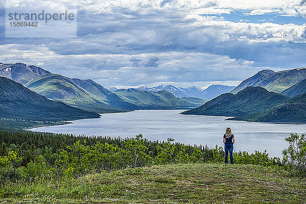 Frau steht und schaut auf einen See und die weiten Yukon Ranges; Whitehorse  Yukon  Kanada